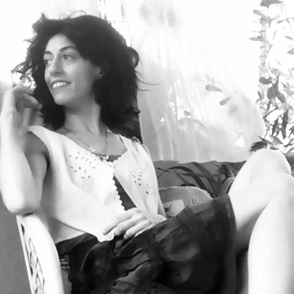 Foto in bianco e nero di Beatrice Condorelli, autrice della poesia, seduta su una poltrona: indossa una canotta bianca e una gonna nera