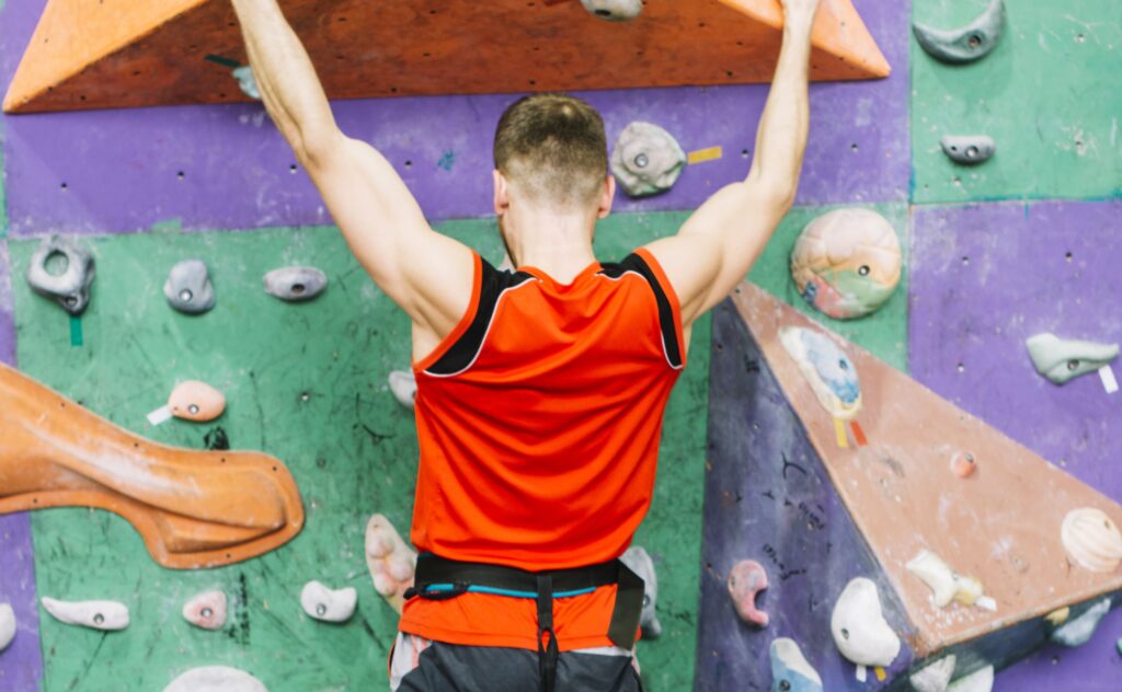 Uomo mentre pratica l'arrampicata sportiva paralimpica, aggrappato a una parete artificiale