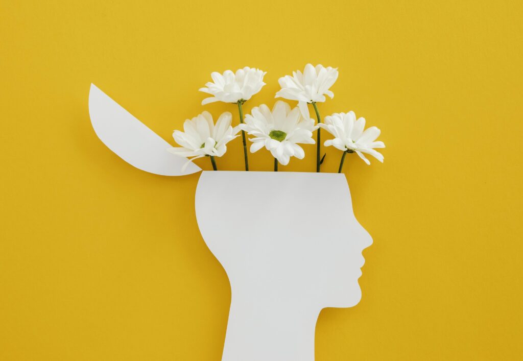 Una testa disegnata in modo stilizzato, aperta sulla parte superiore, con fiori che escono dal cranio