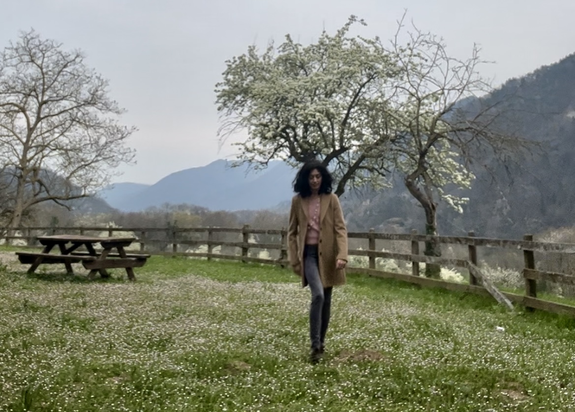 L'autrice di Venerdì (In)Versi Beatrice Condorelli mentre cammina su un prato fiorito circondato dalle montagne