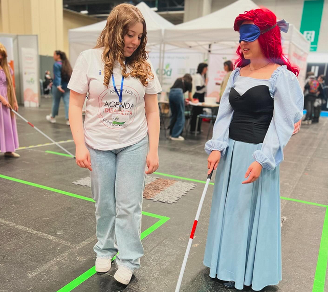 Torino comics 2025 disabilità: una persona bendata in costume prova a camminare con il bastone bianco utilizzato dalle persone cieche